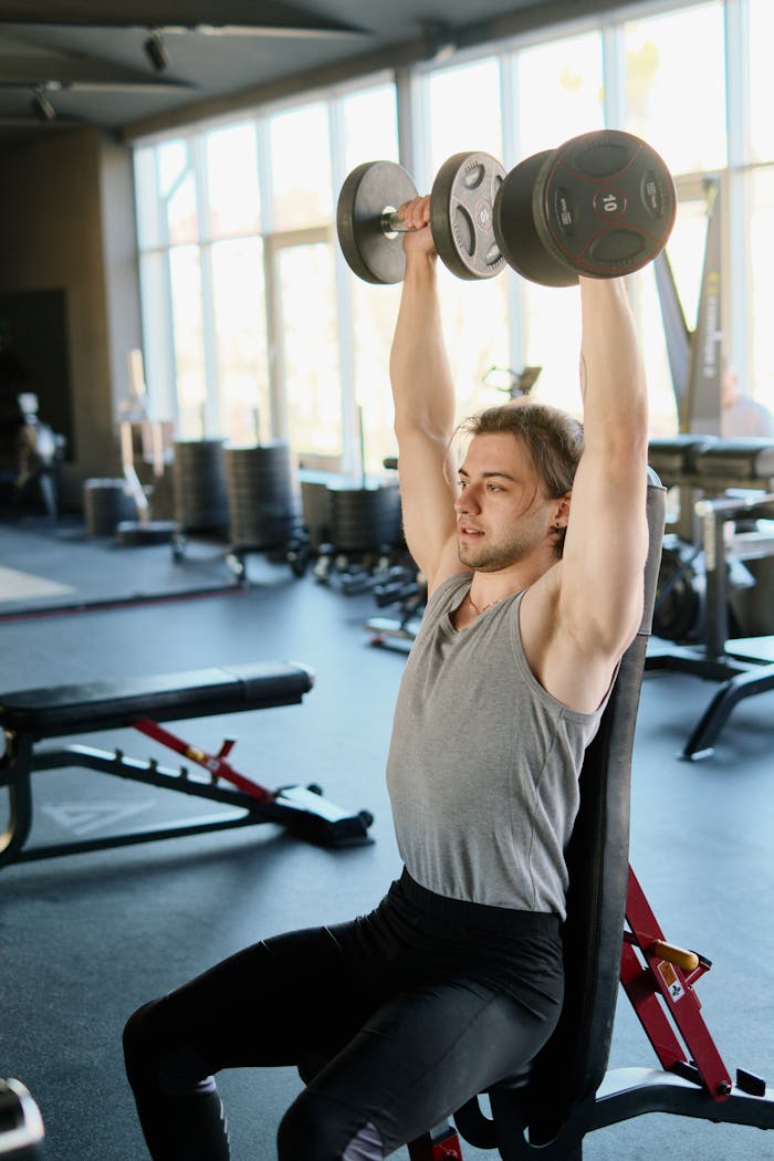 An athletic man lifting dumbbells in a well-equipped gym, showcasing fitness and strength.